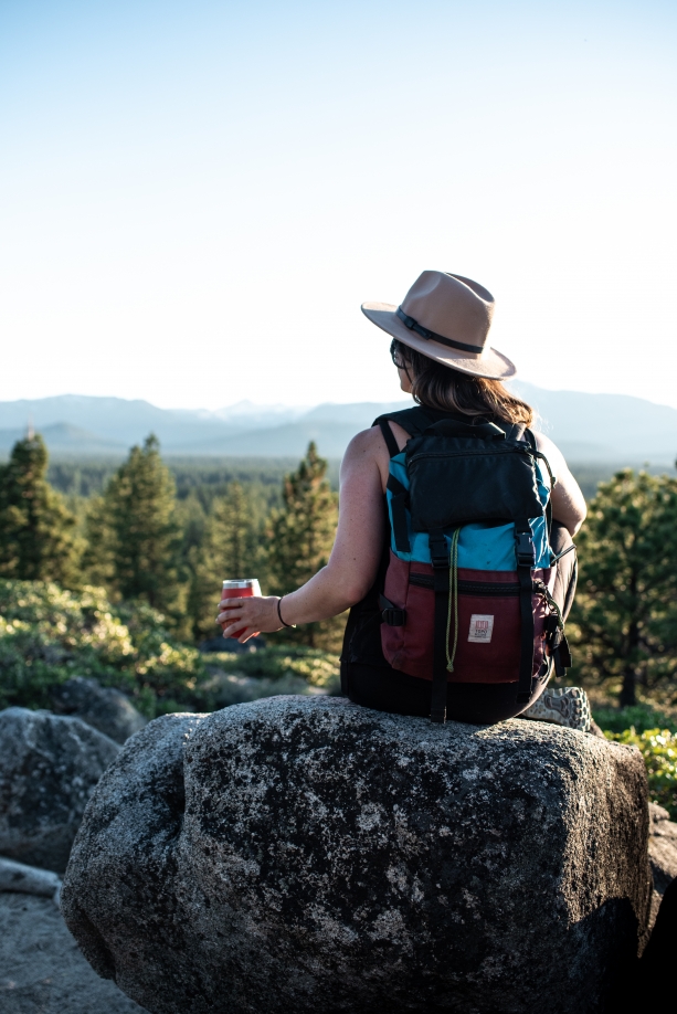girl sitting on rock with backpack